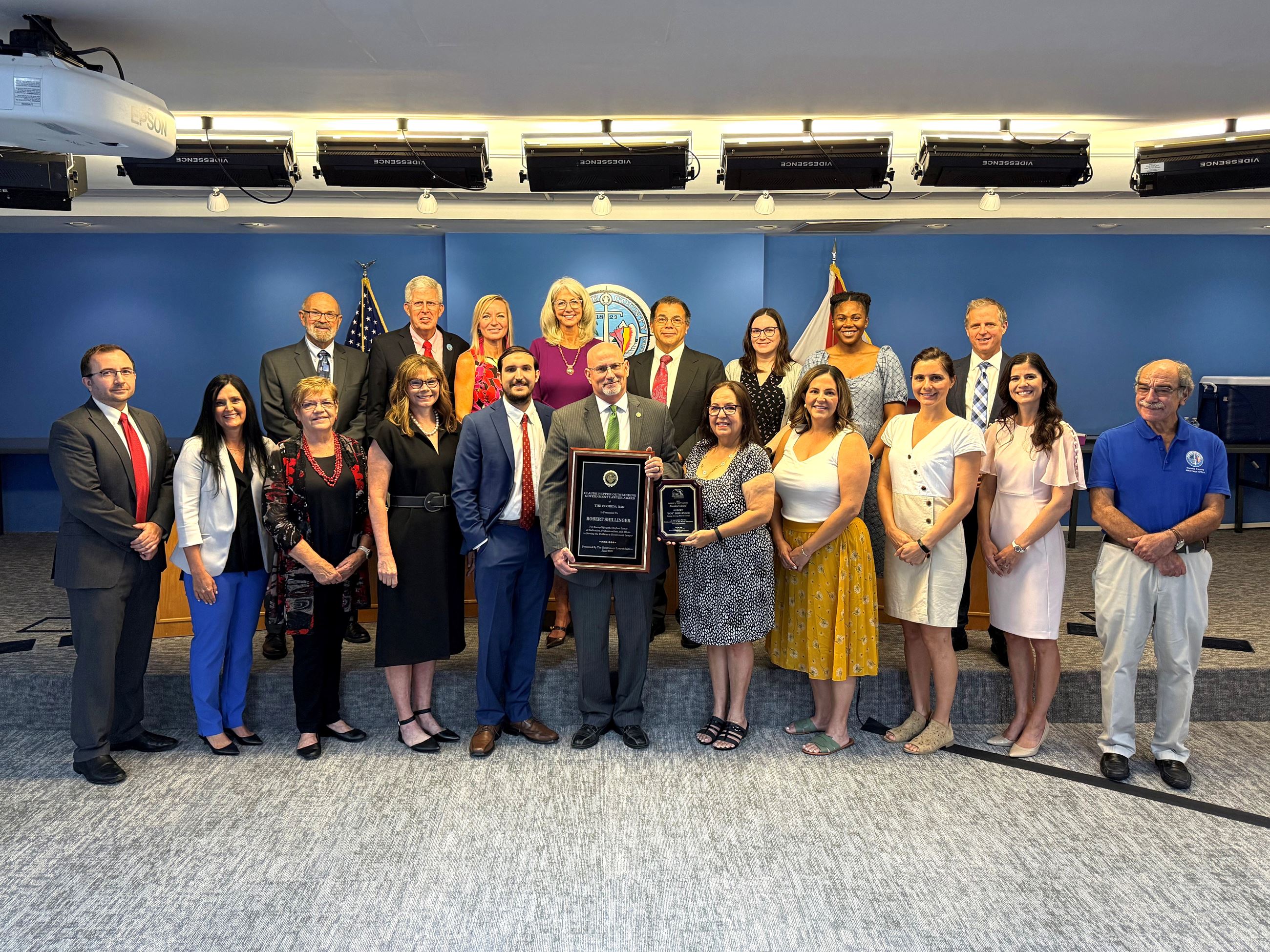 Shillinger surrounded by family and staff at a meeting holding his awards